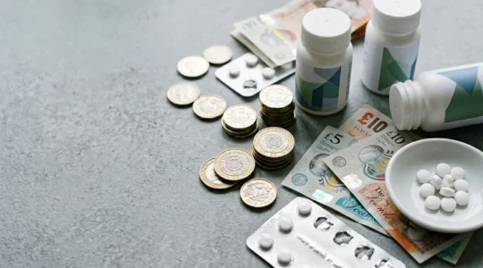 British coins and NHS prescription items arranged on clean surface symbolizing healthcare cost savings strategy