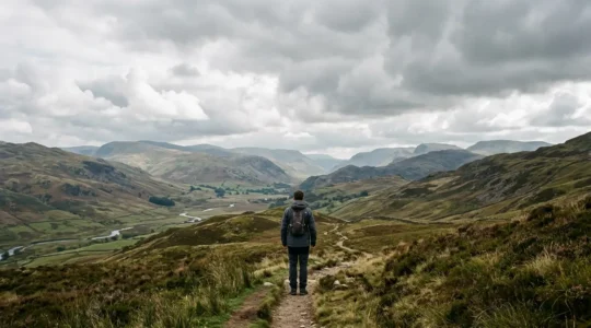 A solitary figure standing at a distance on an overcast British landscape with negative space emphasizing isolation