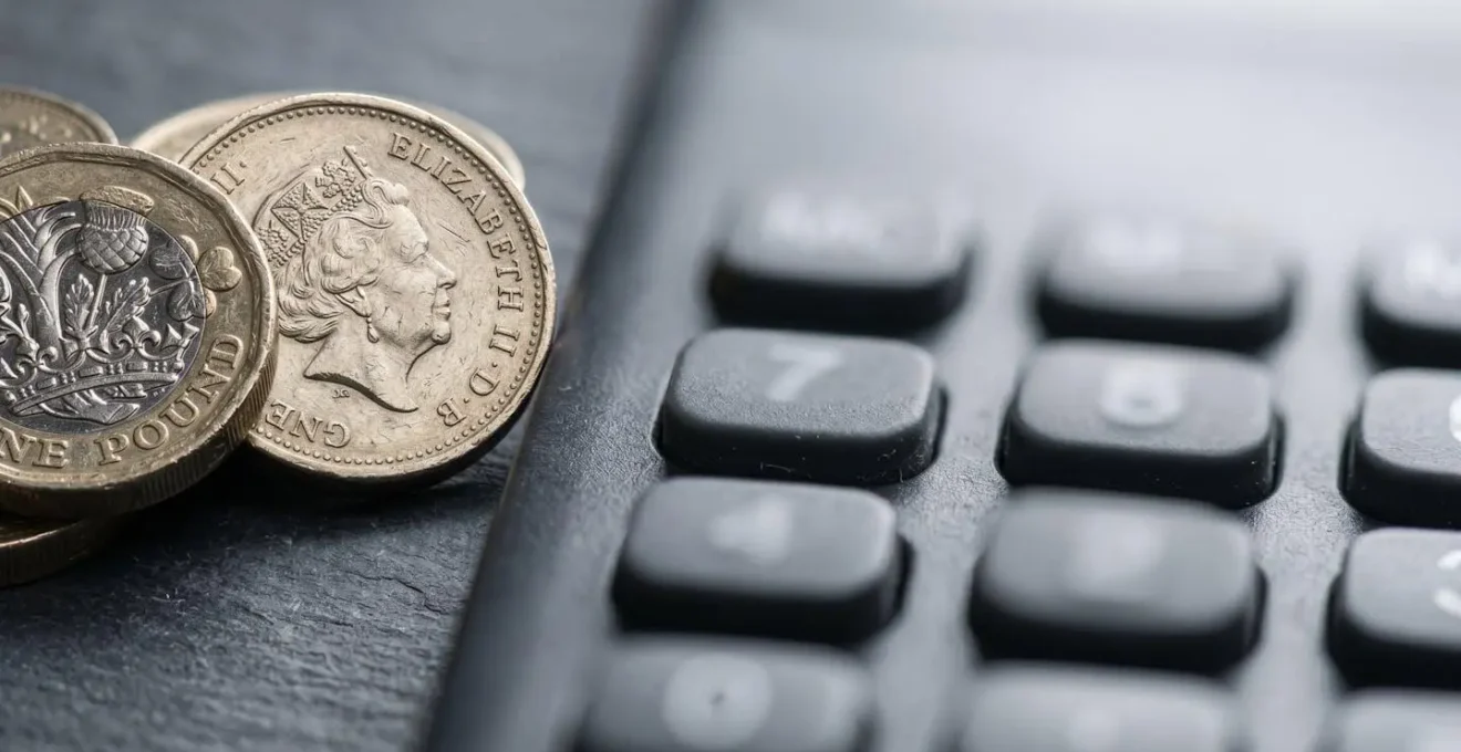 Close-up macro photograph of British currency coins arranged with financial calculator keys showing depth of field