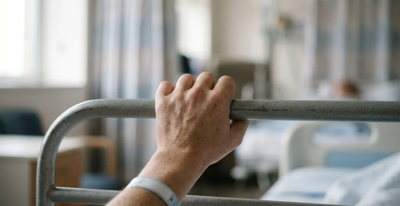 Close-up of patient hand gripping bed rail showing tension caused by sleep disruption in shared hospital ward