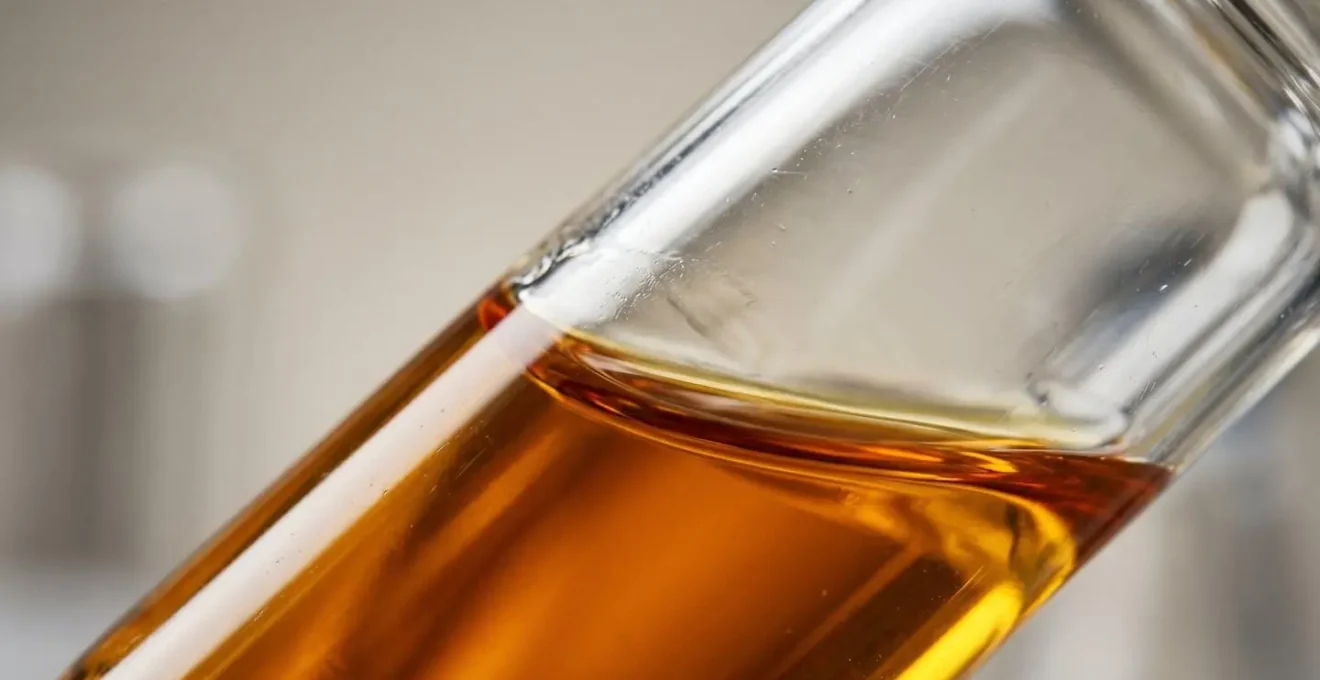 Close-up macro photograph of laboratory glassware with amber liquid representing vitamin D testing with shallow depth of field